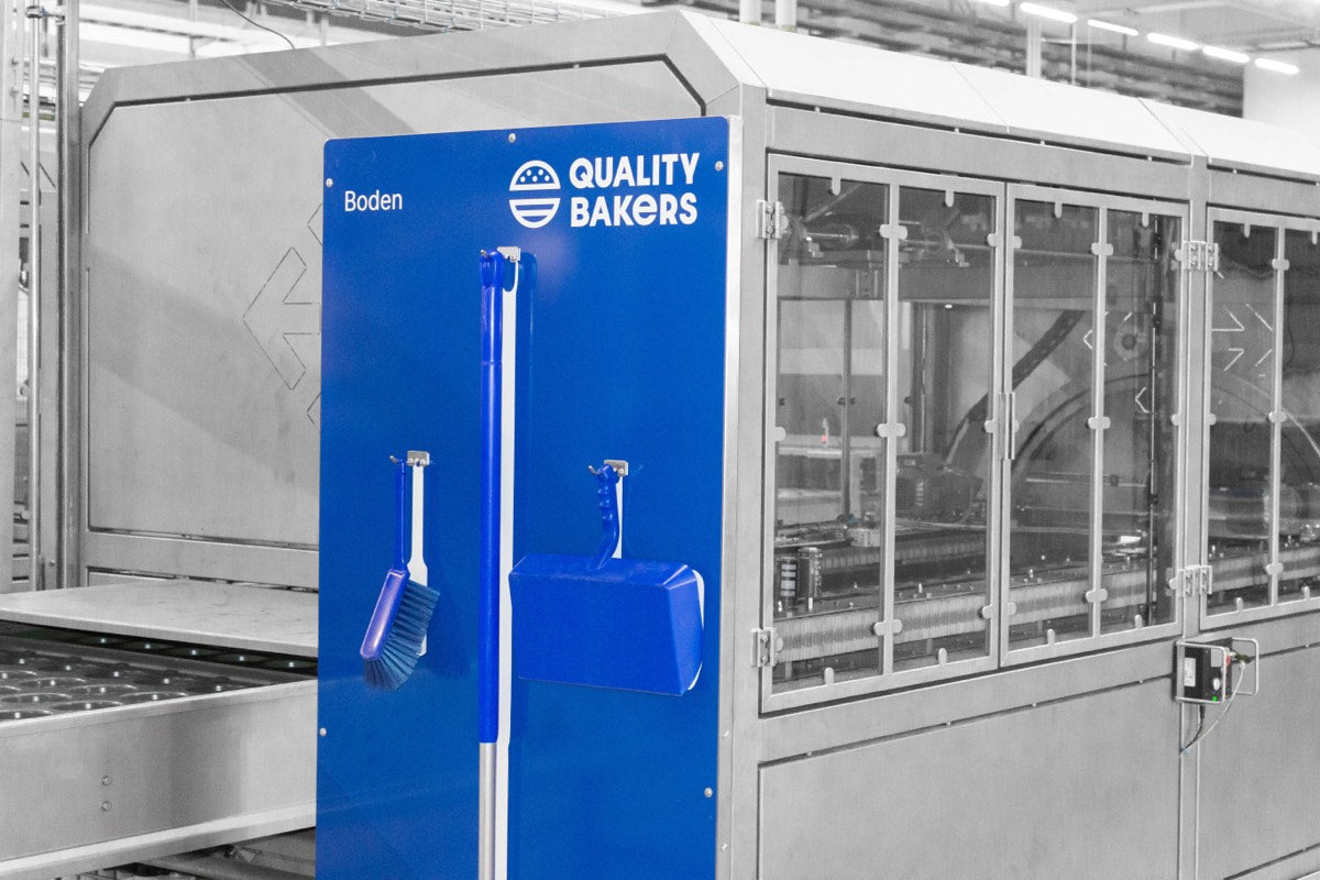 Blaue Reinigungsschattenwand mit Besen und Kehrschaufel vor einer Industrieanlage